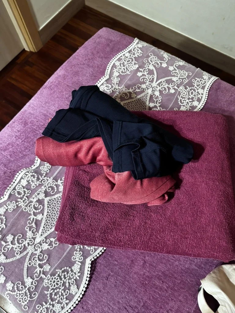 마사지 전 갈아입을 수 있도록 베드 위에 준비된 깔끔한 가운과 타월