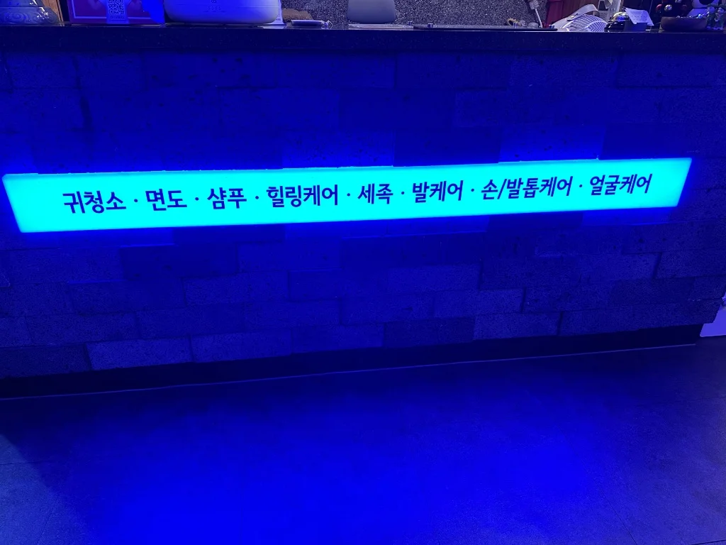 귀청소, 면도, 샴푸, 힐링케어 코스가 적힌 블루 네온 간판