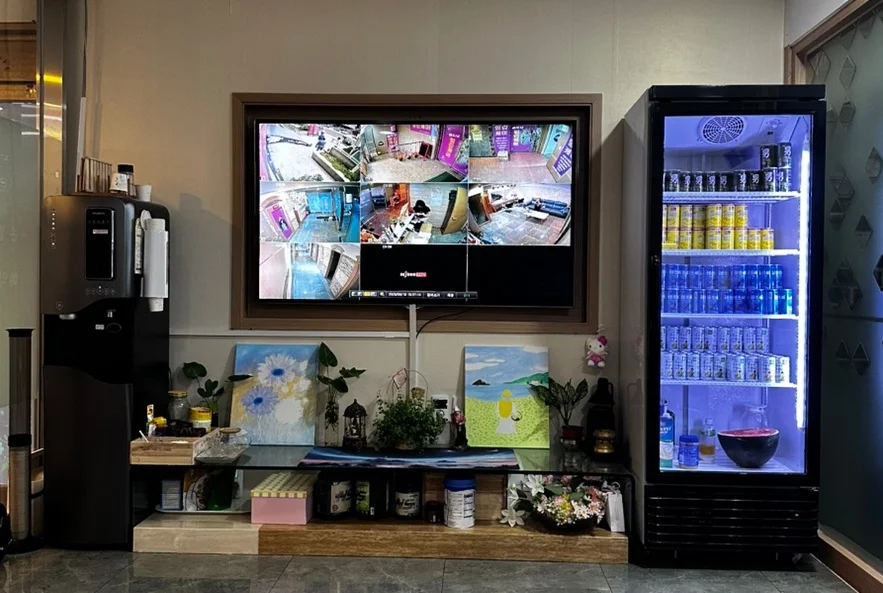CCTV 모니터와 시원한 음료가 가득 채워진 냉장고가 있는 로비 공간